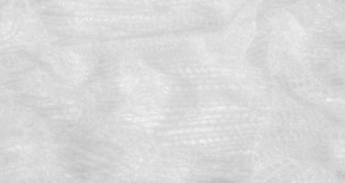 Beyaz dantel kumaşın bulanık görüntüsü, ince parıltısını ve narin desenlerini vurguluyor. Karmaşık doku ve ışık, havadar kalite onu gelin ve resmi etkinlik temaları için mükemmel kılıyor..