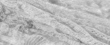 Beyaz kumaş üzerine ince dantel işçiliği, karmaşık ve hassas desenler sergiliyor. Hafif dokusu, hafif bir parıltıyla, kumaşın zarafetini ve inceliğini arttırır.