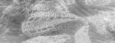 Hassas desenleri olan karmaşık beyaz dantel kumaş bulanıklığı yumuşak dokuları ve zarif akışı sergiliyor. Işık dantele yansıyor ve parıltılı bir etki yaratıyor..