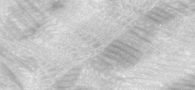 Beyaz dantel kumaş bulanıklığı detaylı desenler ve parıldayan ışık yansımaları gösteriyor. Hassas maddenin yumuşak kıvrımları güzel ve lüks bir görsel kompozisyon oluşturuyor..