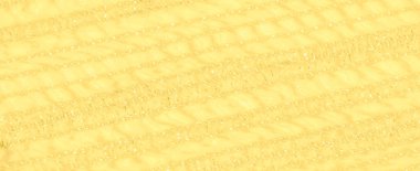 Işıldayan, ışıldayan bir dokusu olan sarı kumaş bulanıklığı. Karmaşık dokuma ve yumuşak kıvrımlar ışığı yansıtıyor, yüzey boyunca parlak, altın bir etki yaratıyor..