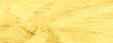 Işıltılı, parlak ipliklerden oluşan, dokulu sarı kumaş bulanıklığı. Detaylı desenler ışık yansımalarıyla birleşerek maddenin içinde parıldayan, ışıldayan ve lüks bir his yaratıyor..