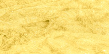 Detaylı dokuları ve ışıl ışıl ışıl parlak ışıkları olan yumuşak sarı kumaştan oluşan bulanık bir görüntü. Kumaşın kıvrımları ve narin desenler lüks ve zarafet hissi veriyor..