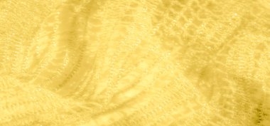 Bu sarı dantelli kumaş, karmaşık ve yumuşak dokusunu gösteren parıldayan yüzeyinin yakın görüntüsünü bulanıklaştırır. Kumaş nazikçe parlıyor, sıcaklık ve lüks hissi yayıyor..