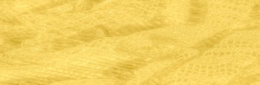Karmaşık parıldayan desenli, altın sarısı bir kumaşın bulanıklığı. Yumuşak kıvrımlar ve parlayan yüzey, moda, dekor veya tekstil tasarımı için ideal parlak bir doku yaratır..