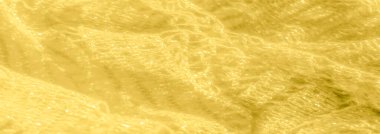 Parlak sarı dantel kumaştan oluşan bulanık bir bulanıklık. Karmaşık desenler ve yumuşak dokuların çarpıcı bir kombinasyonunu gösteriyor. Pırıl pırıl parlayan ışıklar lüks ve sıcak bir atmosfer yaratır..