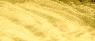 Detaylı dantel desenli parlak sarı bir kumaşın bulanık görüntüsü. Kumaşın parıltısı ve ince dokusu göz kamaştırıcı bir görsel efekt yaratır..