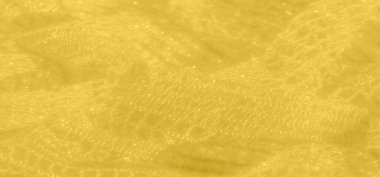 Karmaşık desenlerindeki ışığın zarif oyununu gösteren sönmüş sarı dantel bir kumaş. Işıldayan dokusu derinlik katlarken, zarif kumaşın kıvrımları soyut şekiller oluşturuyor..