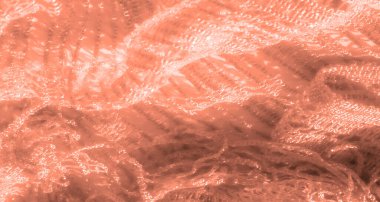 Şeftali dantelli kumaş, ince detaylar ve parlak aksanlı bulanık bir yakın plan. Karmaşık dokuma deseni ve ince ışık oyunu kumaşın tasarımına zarafet ve doku ekler..