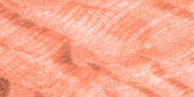 Karmaşık desenli narin şeftali rengi dantel kumaş bulanıklığı, hafif ışıkta parıldayan. Doku, zarif tekstil tasarımları için mükemmel bir dalga benzeri görünüm yaratıyor..