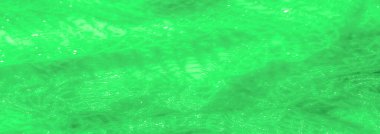 Canlı yeşil dantel kumaştan bulanık, şeffaf ve dokulu yüzeyi ışık yansımalarıyla aydınlatılmış. Parlayan ağ deseni soyut ve yumuşak tasarıma derinlik katar.