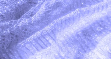 Karmaşık, parlak dokuları olan soluk mavi dantelli bir kumaş. Yarı şeffaf madde hafifçe katlanır, hafif kıvrımlar ve ışığı güzel yakalayan dalgalarla yumuşak bir akış oluşturur..