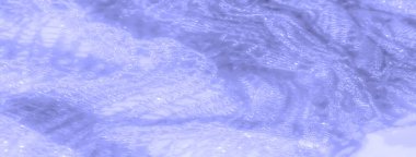 Yumuşak açık mavi renkte bulanık, ince dantel kumaş. Görüntüde akıcı bir doku oluşturan karmaşık desenler içeriyor. Parlayan ışık, maddenin şeffaf olduğunu vurgular.