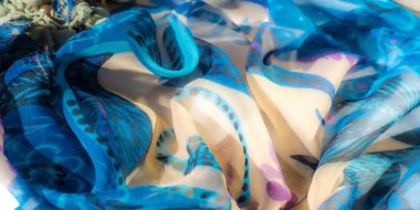 Mor ve bej renkli, karmaşık çiçek desenleri olan parlak mavi kumaş. Görüntü, kumaşın katıksız dokusunu ve narin, birbiriyle zıt renklerde dönen tasarımlarını vurgular..