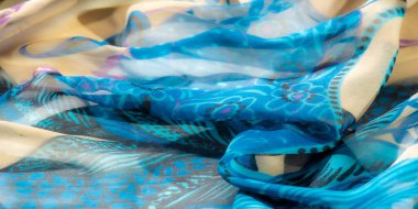 Dalgalı mavi ve bej kumaştan bulanık. Karmaşık mor çiçek izleri ve dekoratif püsküllerle süslenmiş. Dinamik doku ve canlı renk paleti büyüleyici ve zarif bir tasarım sunuyor..