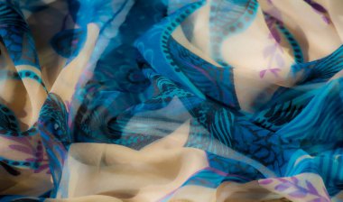 Açık bej ve mavi kumaş bulanıklığı soyut çiçek motifleri ve hassas ponpon aksanlarıyla. Yumuşak malzeme zahmetsizce akar, zarif kıvrımlar oluşturur ve moru gözler önüne serer