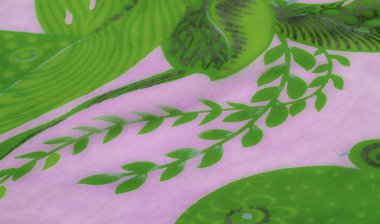 Süzülen yeşil ve lavanta çiçeği desenli saf kumaştan bulanık bir yakın çekim. Hassas malzeme yumuşak, akıcı bir doku yaratıyor, karmaşık tasarımları vurguluyor..