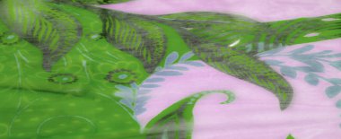 Bulanık hafif lavanta ve karmaşık yaprak ve çiçek desenli yeşil kumaş yumuşak şifon kumaşının ince tabakalarını ve havadar dokusunu ortaya çıkarmak için nazikçe örtülmüş..