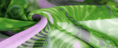 Yumuşak pastel tonlarında, yeşil ve lavanta renginde, çiçekli ve yapraklı karmaşık tasarımlar içeren akışkan bir kumaşın bulanıklığı. Saf malzeme havayla hassas ve sofistike bir dokunuş sunuyor.,