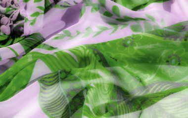 Şeffaf yeşil ve lavanta kumaştan oluşan bulanık, soyut çiçek desenli, yumuşak, akıcı bir doku yaratıyor. Karmaşık tasarım, materyalin nazik dalgalarıyla güzel bir şekilde harmanlanır..