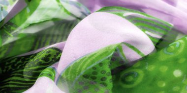 Bulanık lavanta ve zarif çiçek desenli yeşil katıksız kumaş. Işık ve kıvrımların oyunu yumuşak, akışkan bir etki yaratır. Maddenin hassas ve canlı doğasını yakalar..