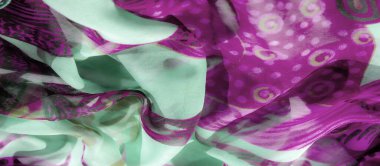 Nane yeşili ve mor kumaşlı, kıvrımlı çiçekli ve soyut desenli bulanık bir yakın plan. Saf malzeme ışık ve gölgenin eğlenceli etkileşimine olanak sağlıyor, hassas dokusunu vurguluyor..