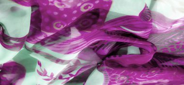 Karmaşık mor soyut desenler, yumuşak, soluk yeşil kumaşın üzerine katmanlı çiçek elementleriyle sarmalanmış. Renklerin ve dokuların oyunu dinamik ve tuhaf bir estetik yaratıyor..