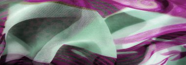 Mor ve nane yeşili renklerin dinamik bir karışımı. Saf kumaş, karmaşık çiçek desenleri ve akış dokusuyla vurgulanmış. Madde hareket ve hafiflik hissi uyandırıyor..