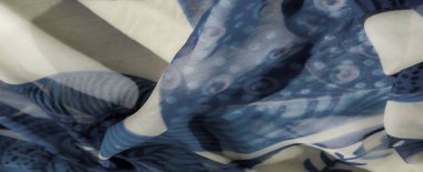 Açık mavi ve bej soyut desenlere sahip karmaşık bir kumaşın bulanıklığı. Tasarım dairesel şekiller ve ince çizgiler sergiliyor, kumaşa yumuşak ve akıcı bir görünüm veriyor..