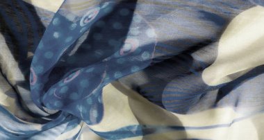 Yumuşak kıvrımlar ve yumuşak dokularla vurgulanmış kıvrımlı mavi ve bej bir kumaşın bulanıklığı. Kumaş, soyut ve çiçek motifleriyle doğal bir akış yaratır..