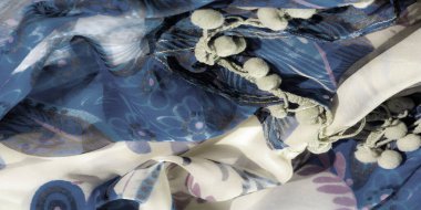 Mavi ve bej tonlarında çiçek desenleri ve soyut girdap desenleri olan hassas bir kumaşın bulanıklığı. Kumaş doğal zarafetle akıyor, karmaşık ve detaylı tasarımını sergiliyor..