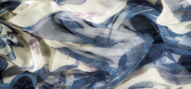 Yumuşak maviler ve bej tonlarda girdap şeklinde çiçekli ve soyut desenli narin bir kumaşın bulanıklığı. Yarı saydam madde rüya gibi ve akıcı bir etki yaratıyor..