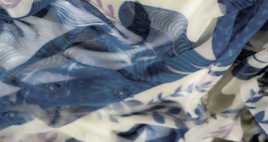 Detaylı soyut çiçek kumaşı bulanıklığı. Yumuşak mavi, mor ve bej renkleri var. Katlar ve saydam katmanlar kumaşa bir derinlik ve hareket hissi ekler..