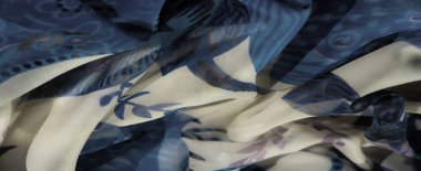 Mavi ve bej kumaş üzerinde soyut desenlerin bulanıklığı yumuşak ve zarif bir renk etkileşimi yaratıyor. Kumaşlar nazikçe katlanır ve ince tasarımlar sakin, akıcı bir estetik yayar.