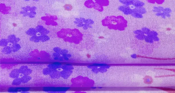 Açık mor bir kumaş, küçük mavi ve menekşe çiçekleri ve ince sapları olan bulanık bir görüntü, yinelenen desenler halinde düzenlenmiş, yumuşak, rengarenk bir estetik sunuyor..