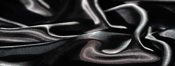 Размытие черной атласной ткани абстрактными складками, с резкими бликами и глубокими тенями, создающими высококонтрастное взаимодействие между светом и тьмой на гладкой поверхности.