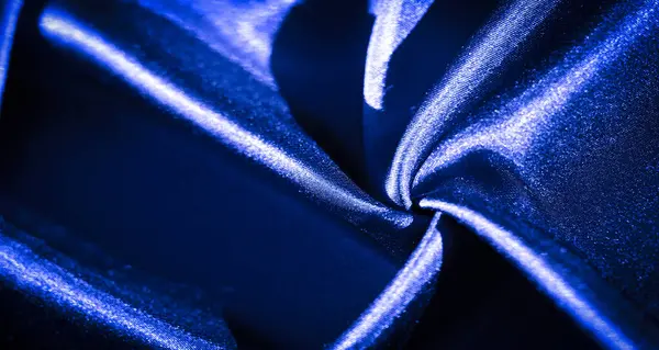 Yumuşak kıvrımlı ve ipek kaplamalı zengin mavi kumaş. Işık pürüzsüz dokuyu vurgular ve kumaşın lüks, akışkan görünümünü güçlendirir..
