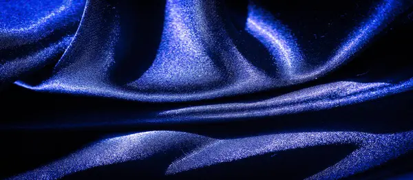 Saten benzeri, zengin, canlı mavi bir kumaş, zarif bir şekilde akan ve narin kıvrımlar oluşturan. Yumuşak ışığın altında parlayan ipek dokular sanatsal ve lüks bir görsel ekran oluşturuyor..