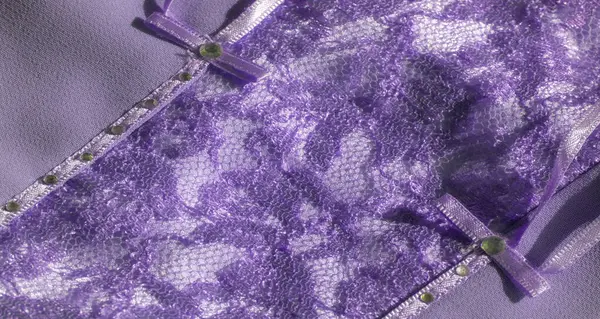 Bu mor dantel kumaşın karmaşık tasarımı yumuşak bir ışıltıyla geliştirilmiş örgü ve çiçek elementlerinin bir kombinasyonunu içeriyor. Tekstil, moda ve dekoratif amaçlar için ideal..