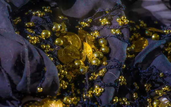 Parlak altın paralar ve boncuklarla süslenmiş narin donanma kumaşı. Kumaşın yumuşak şeffaflığı ve metalik aksanlar arasındaki etkileşim ona zengin ve süslü bir görünüm kazandırıyor..