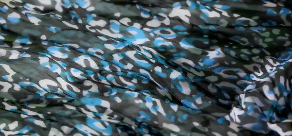 Mavi, beyaz ve yeşil tonlarda renkli bir kamuflaj kumaşının bulanıklığı. Yumuşak kıvrımlar halinde yakalanarak dokuyu ve deseni arttırıyor. Sanatsal düzenleme kumaşı verir.
