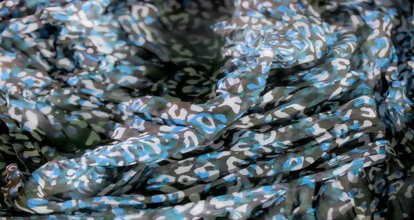 Yumuşak kıvrımlı mavi, beyaz ve yeşil tonlarda canlı bir kamuflaj kumaşı. Soyut desen, tekstil tasarımı için ideal derinlik ve hareket dinamik bir his yaratır..