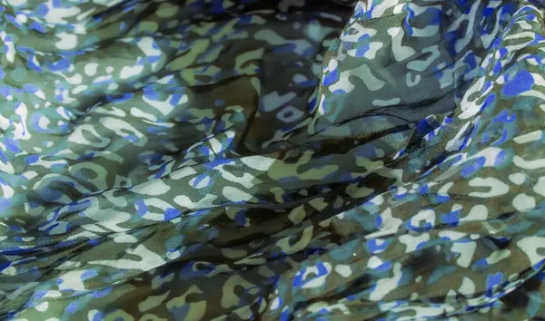 Siyah bir tabanda yeşil, mavi ve beyaz karışımıyla soyut kumaş desenini bulanıklaştırarak dinamik ve akışkan bir etki yaratırız. Kumaşın dokusu yumuşak ve şekilleri düzensiz..