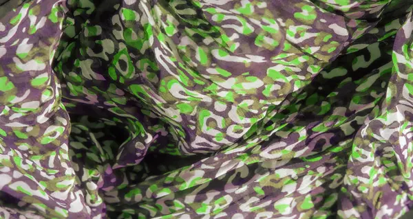 Saf kumaş boyunca akan yeşil, siyah ve beyaz şekiller organik hareket ve akıcılık hissi verir. Soyut desen, moda tasarımı için mükemmel görsel olarak çekici bir doku yaratıyor.