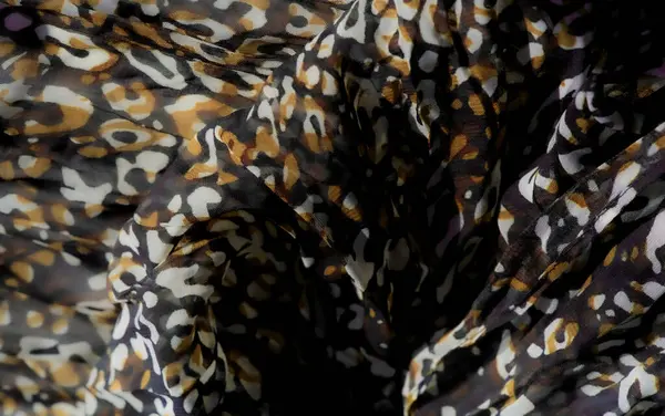 Dönen mor, sarı ve kahverengi desenli dinamik kumaş bulanıklığı. Kumaşın kıvrımları ve karmaşık dokusu tasarıma enerji ve derinlik ekler, moda veya ev dekorasyonu projeleri için mükemmeldir..