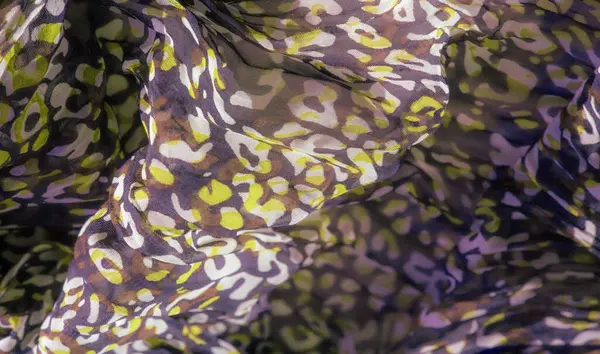 Mor, yeşil ve kahverengi renklerin karışımını gösteren bulanık kumaş eşsiz bir tasarım yaratıyor. Kumaşın dalgalı dokusu ve kıvrımları akıcılık ve zarafeti çağrıştırıyor..