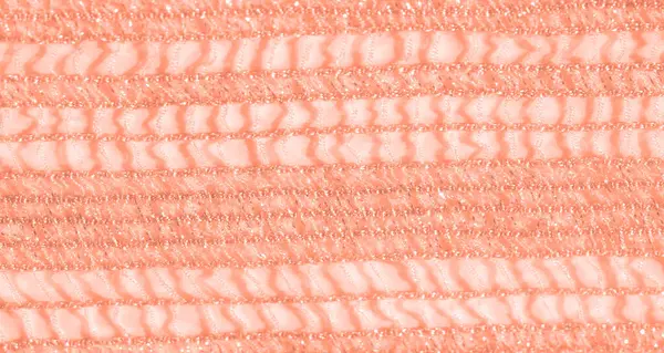 Yumuşak mercan renklerinde narin, karmaşık bir dantel kumaşın bulanıklığı. Doku, parıldayan ışıkla vurgulanır, ona rüya gibi ve ruhani bir görünüm verir..