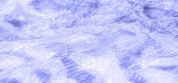 Bulanık - açık mavi renklerde yumuşak dantelin parıldayan dokusu. Dantelin karmaşık ve narin desenleri yumuşak ışıkta güzel bir şekilde yakalanmış rüya gibi bir etki yaratıyor..