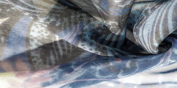 Açık mavi ve yumuşak bej renkli, girdap şeklinde soyut tasarımları olan hassas bir kumaşın bulanıklığı. Akan desenler nazik dalgalara benziyor. Bu pürüzsüz tekstil üzerinde rahatlatıcı bir görsel etki yaratıyor..