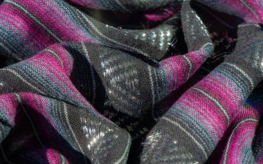 Pembe ve mor çizgilerle dokunmuş siyah bir kumaşın bulanıklığı, lüks ve sanatsal bir görünümü çağrıştıran parıltılı röflelerle dolu zengin bir doku yaratıyor..